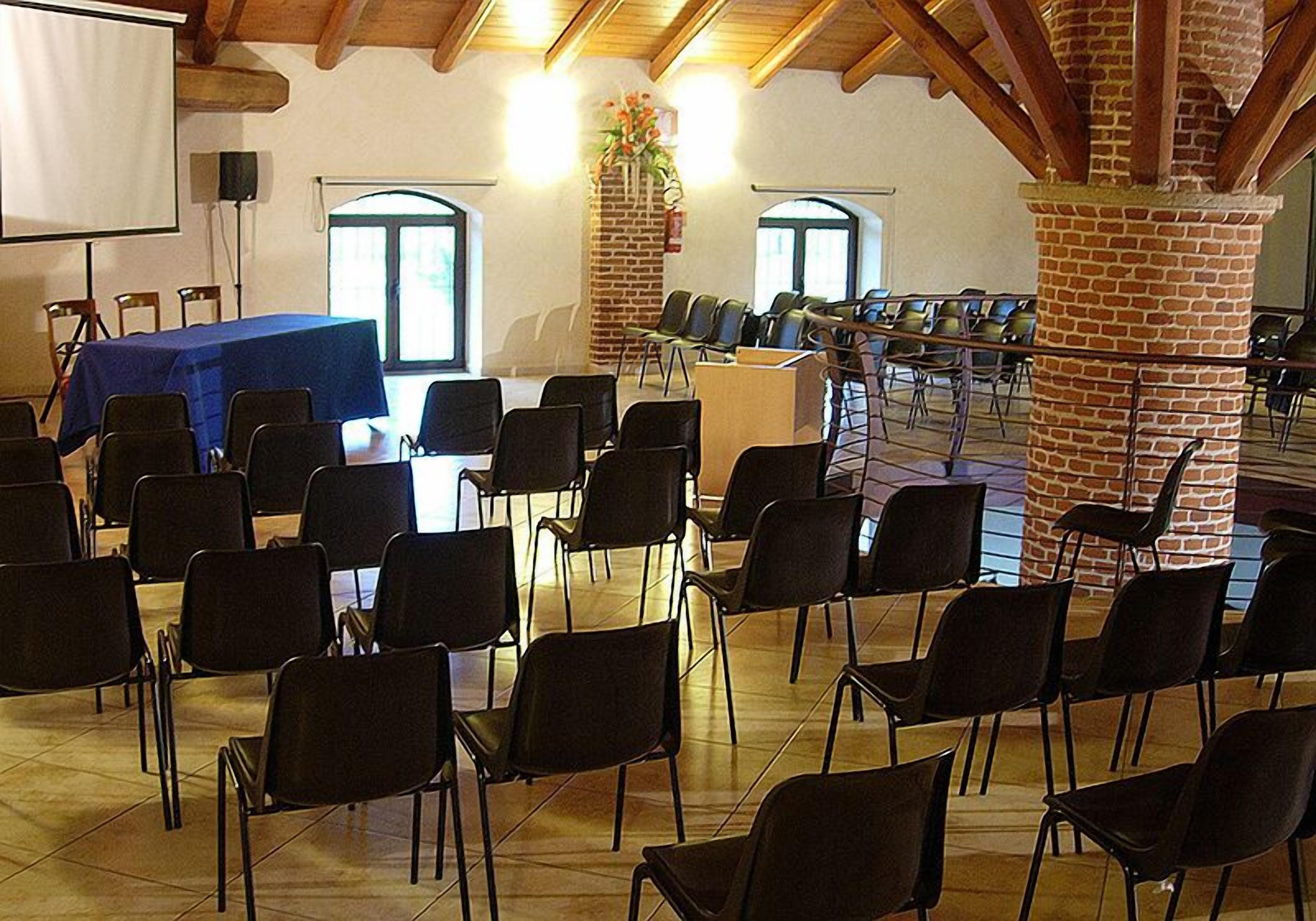 Een vergaderzaal met rijen stoelen, een spreekgestoelte en een projectiescherm.