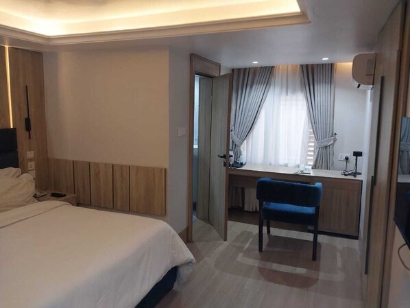 A hotel room with a bed, a desk, a chair, and a mirror. - Centurion Apartments Limited (Abuja)
