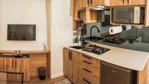 A compact kitchen with wooden cabinets, a built-in microwave, a stove, and a dishwasher. - Centurion Apartments Limited (Abuja)