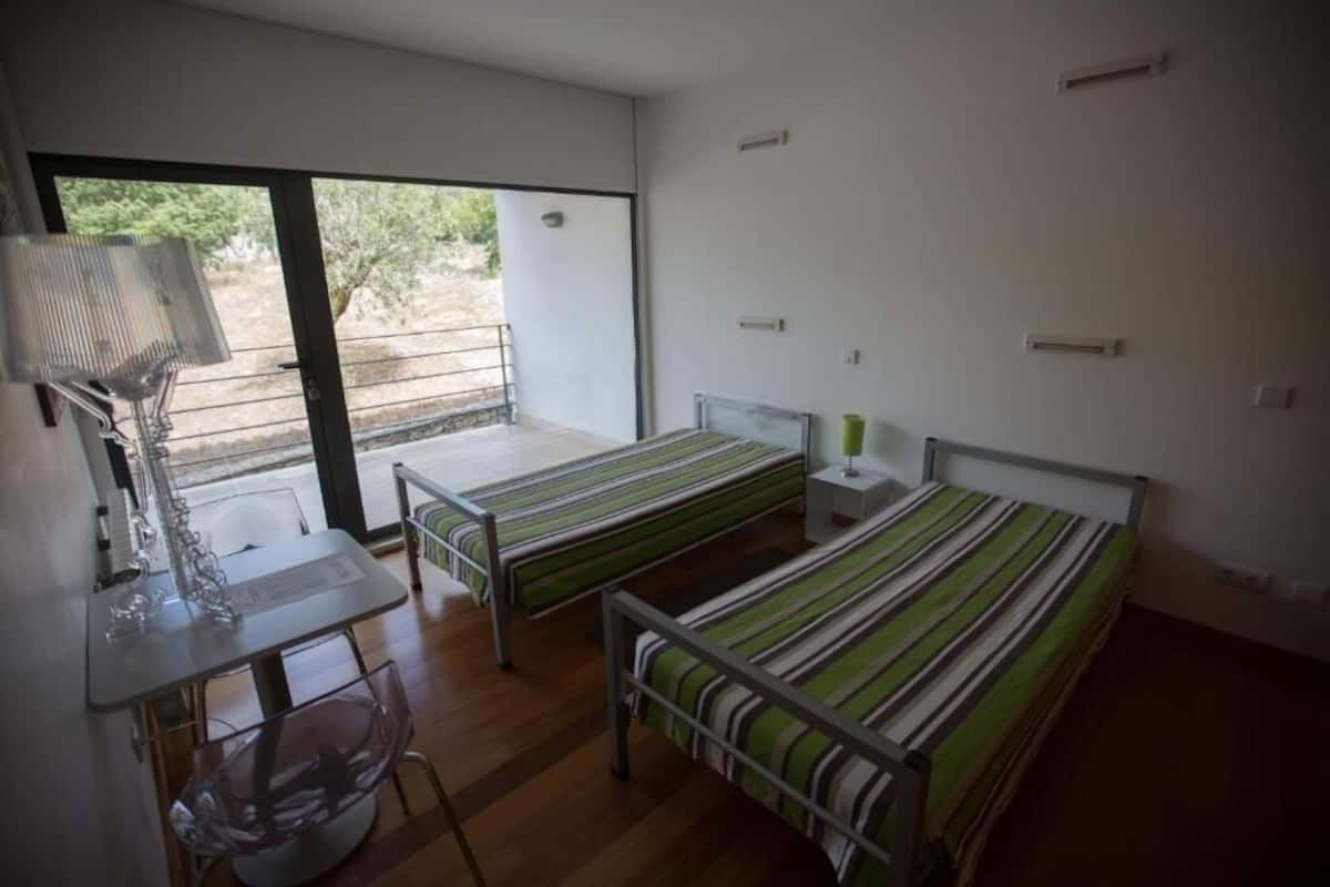A modern room with two single beds, a desk, and a chair.