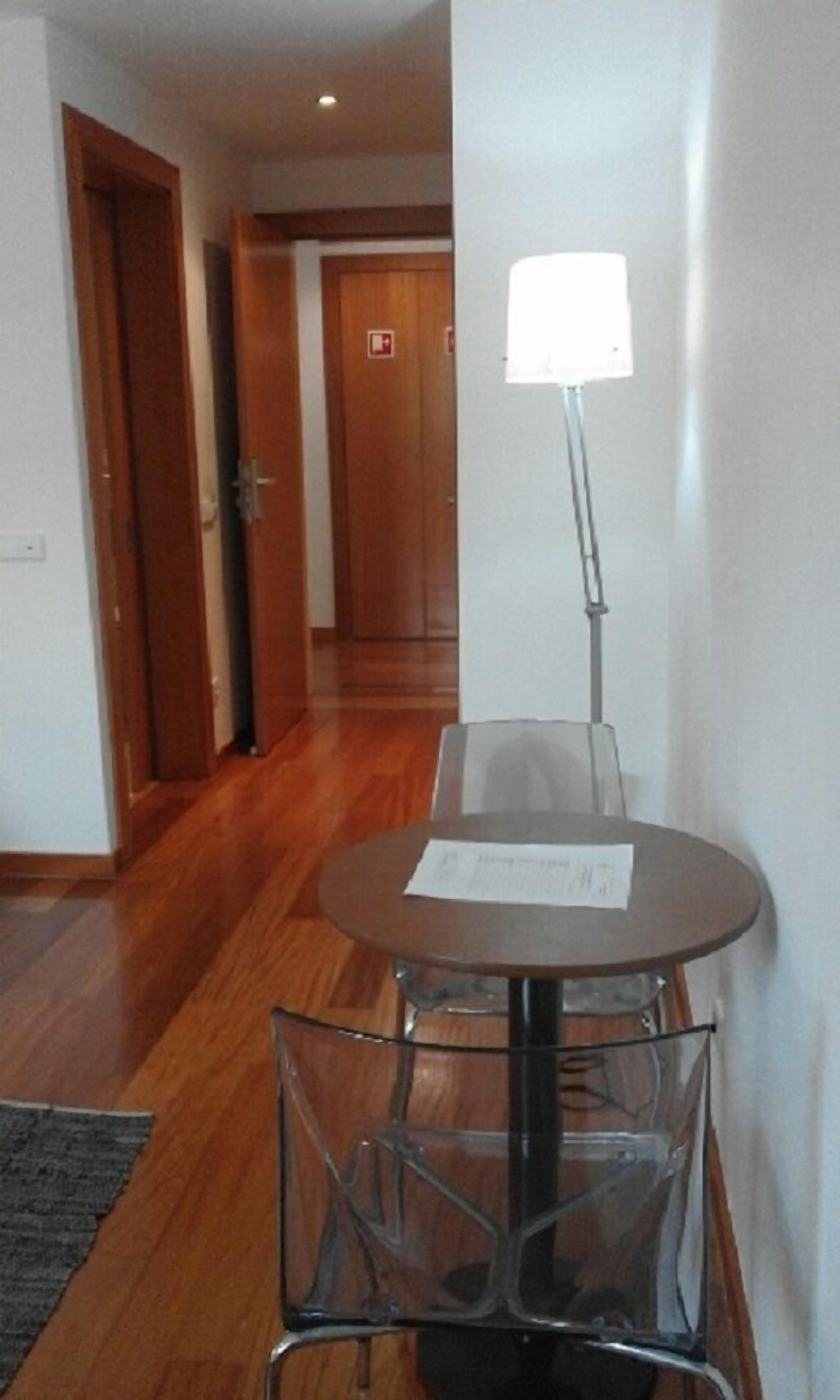 A small, round table with a chair, a lamp, and a piece of paper on the table.