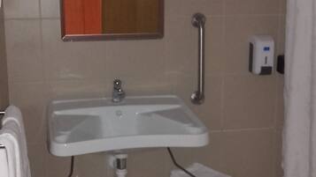 Une salle de bain avec un lavabo blanc, un miroir, un porte-serviettes, un sèche-mains et un rideau de douche.