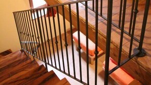 A wooden staircase with metal railings leading to a room with a red sofa. - Girfalco - Country House - Bed&Breakfast (Urbino)