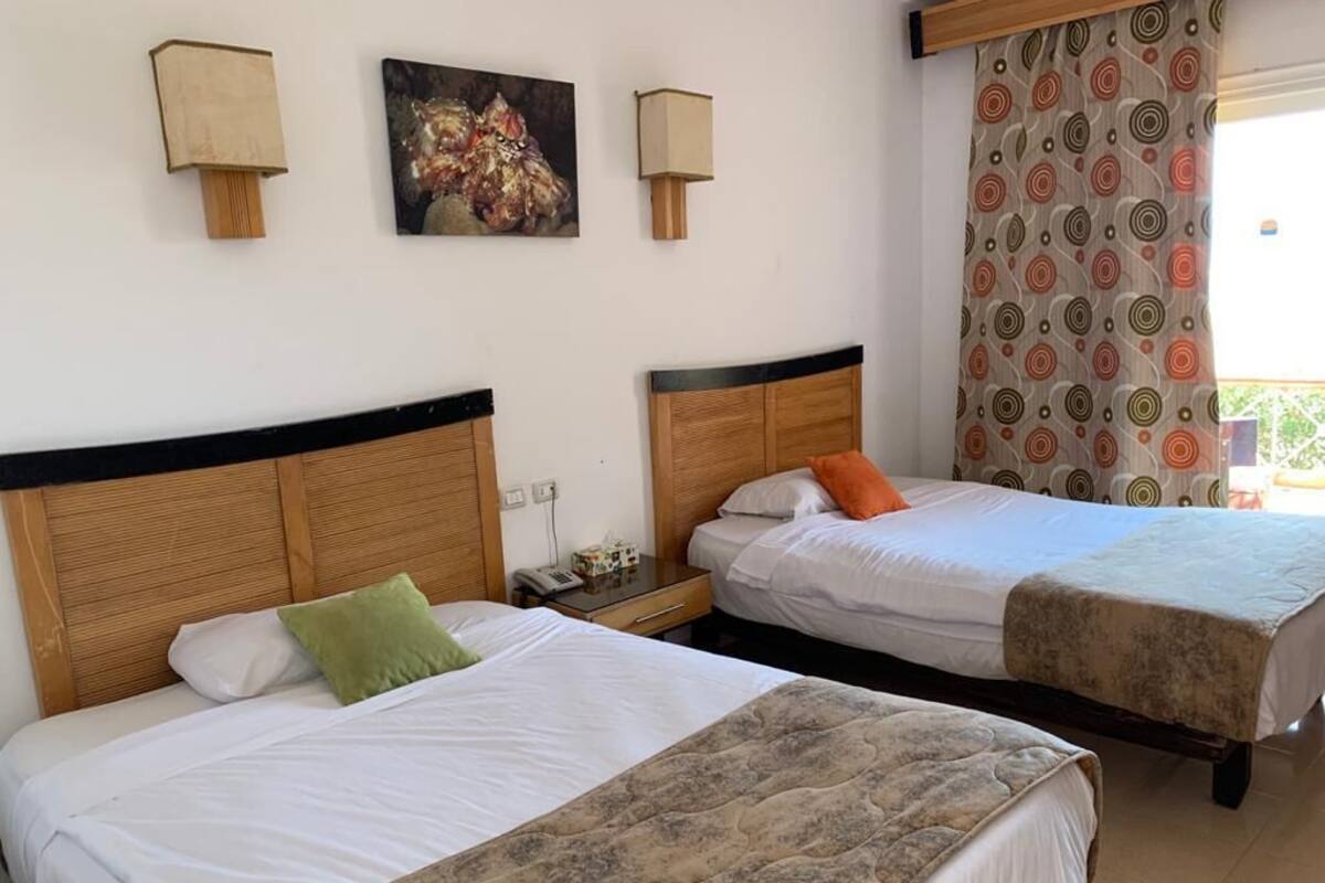 Two single beds with wooden headboards, a nightstand, a lamp, and a painting on the wall.