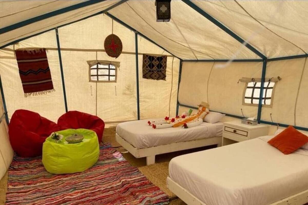 A tent with two beds, a red bean bag, and a green bean bag.