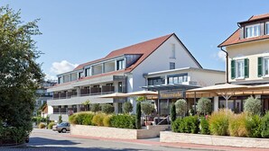 A hotel with a restaurant on the ground floor, multiple flags, and a well-maintained garden area.