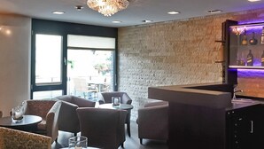 A modern lounge area with comfortable seating, a bar with a stone accent wall, and a view of the outdoors.