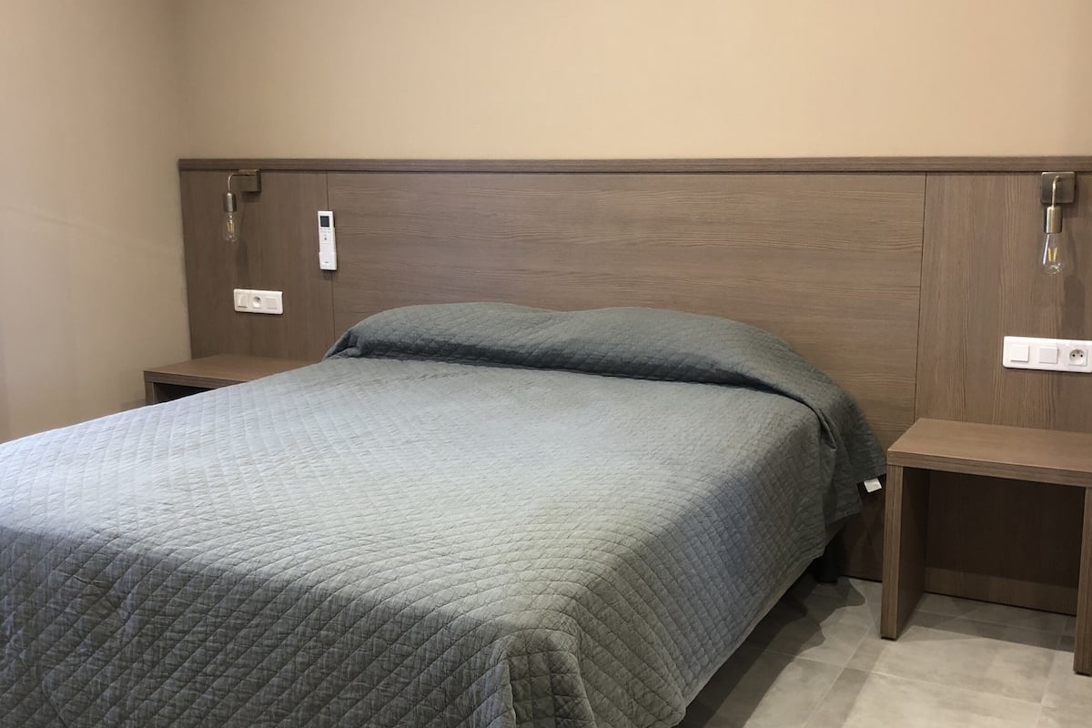 A bedroom with a bed, nightstands, and a headboard.