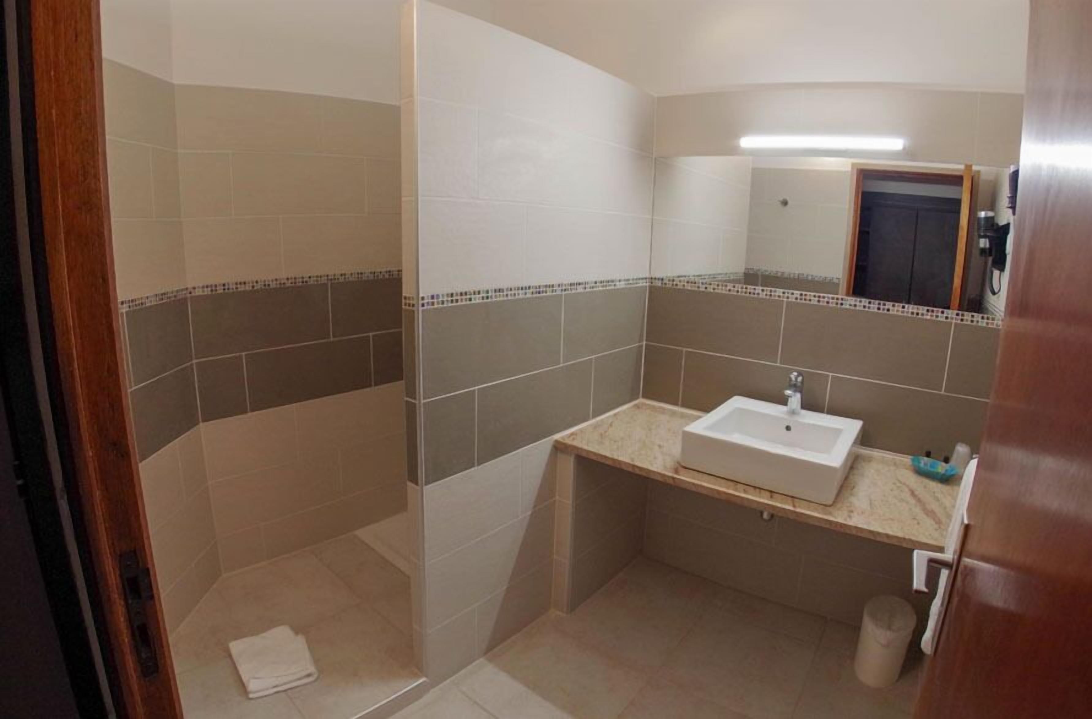 Un baño con ducha, lavamanos y espejo.
