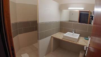 Un baño con ducha, lavamanos y espejo.