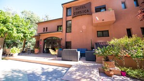 Un hotel con mesas al aire libre y macetas con plantas.