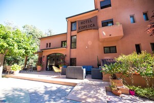 Un hotel con mesas al aire libre y macetas con plantas.