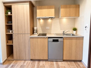 A modern kitchen with wooden cabinets, a built-in dishwasher, and a coffee maker. - Hôtel Corsica (Ota)