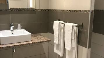 A modern bathroom with a white sink, a mirror, and two towels hanging on a rack.