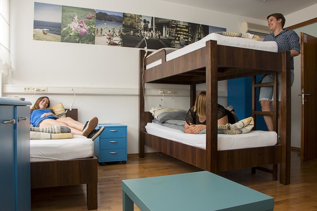 Una habitación tipo dormitorio con literas, un escritorio y un armario azul.