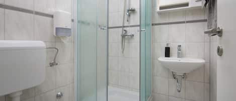 A modern bathroom with a glass-enclosed shower, a white sink, and a toilet.