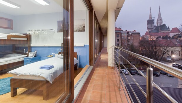 A balcony with a view of a cityscape, including a church spire. - Hostel Bureau (Zagreb)