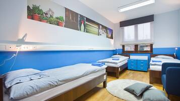 Habitación tipo dormitorio con dos camas individuales, un escritorio, una silla, una ventana y un televisor instalado en la pared.