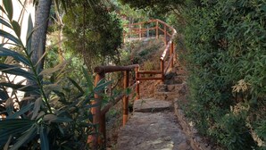 A stone staircase with wooden railings, surrounded by dense foliage. - Sosventos Village (Teulada)
