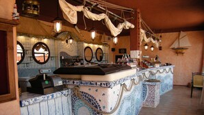 A bar area with a mosaic tiled counter, multiple mirrors, and hanging lanterns. - Sosventos Village (Teulada)