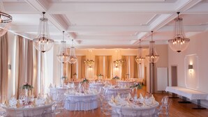 Un salón de banquetes con mesas redondas, sillas transparentes y candelabros de cristal.