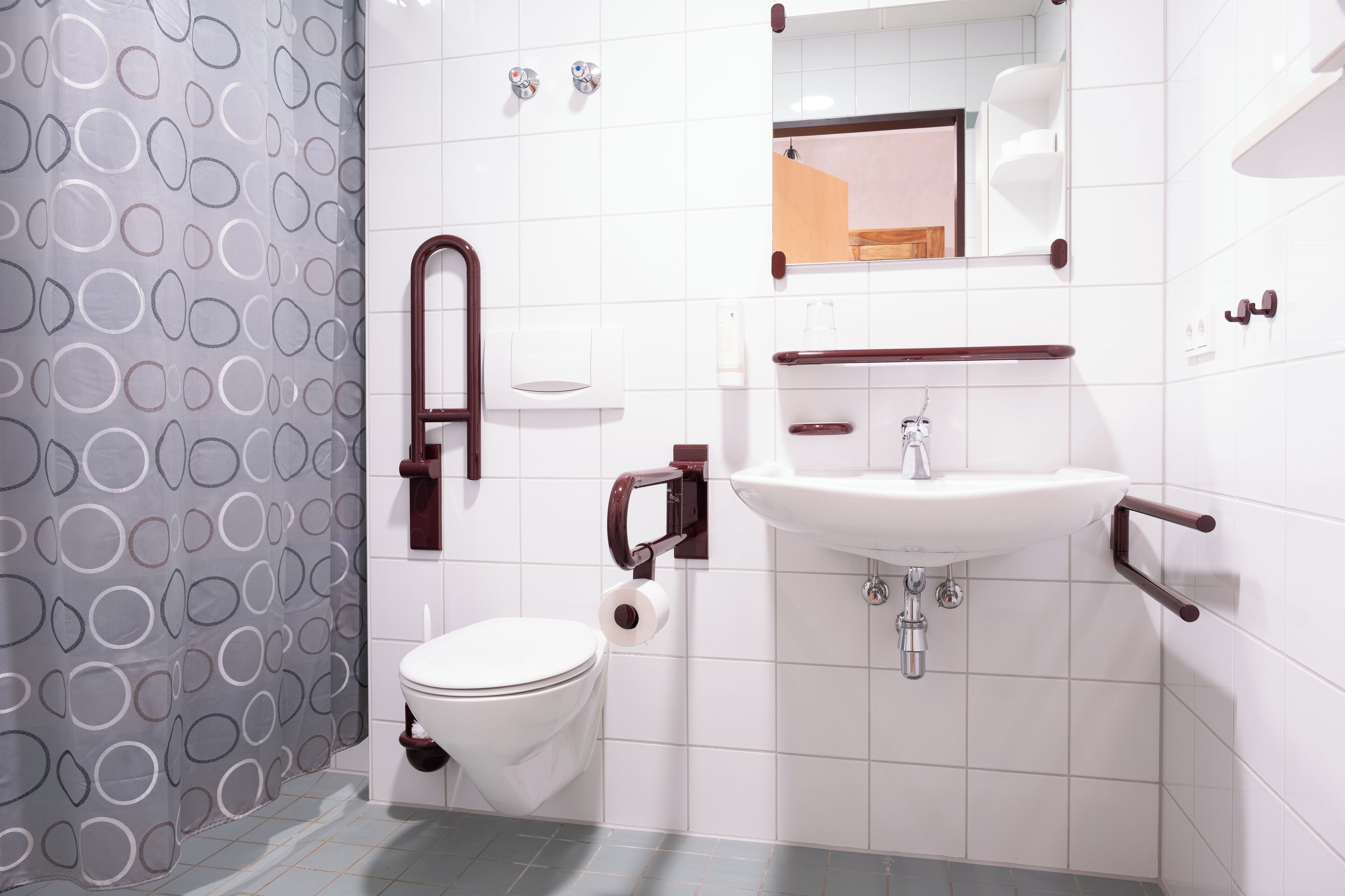 A modern bathroom with a toilet, sink, and mirror.