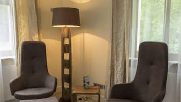 A room with two armchairs, a floor lamp, and a small table.