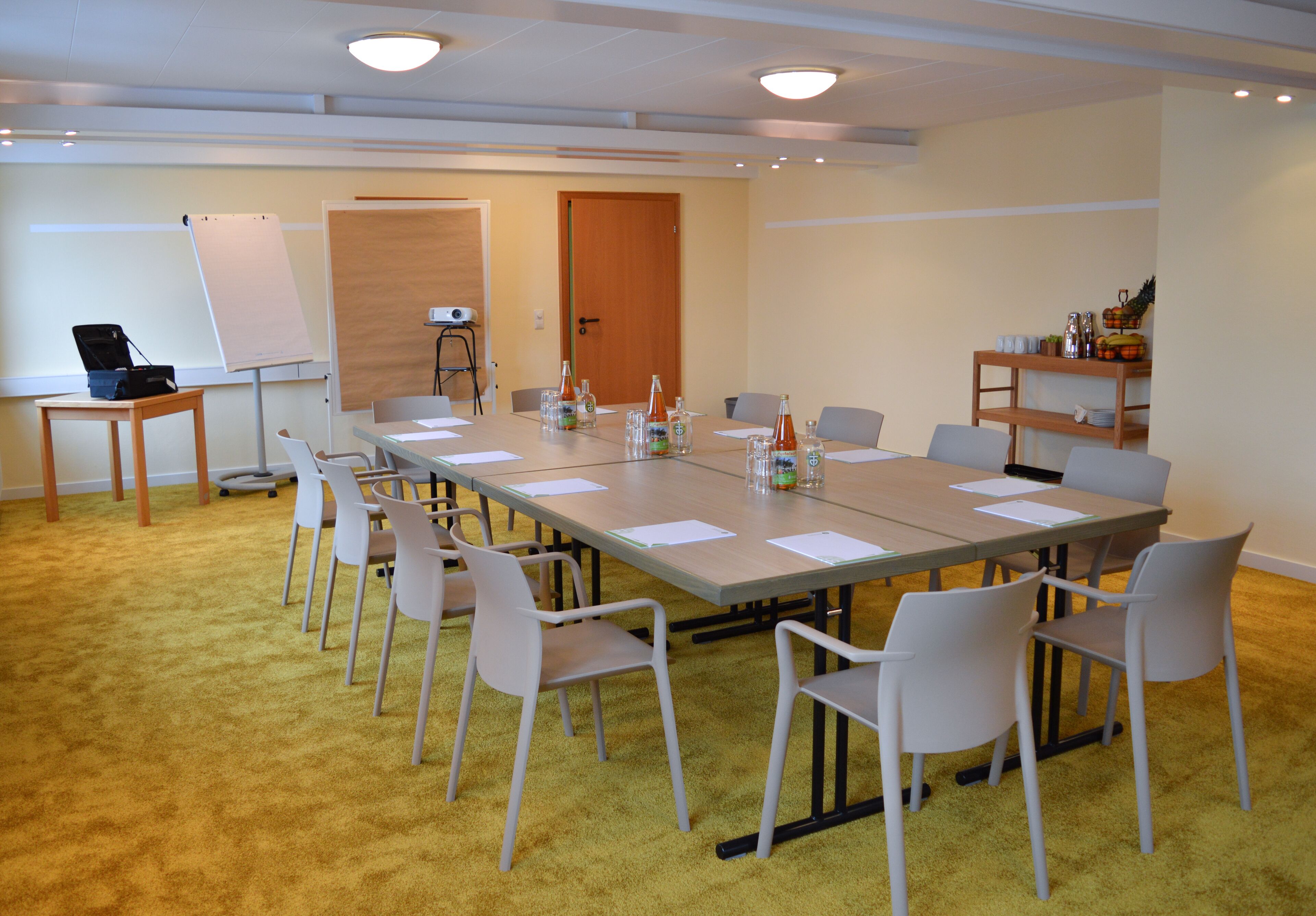 A conference room with a long table, white chairs, a whiteboard, and a projector.