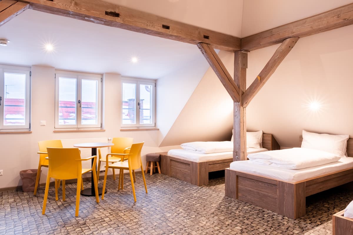 Una habitación con techo de madera, una cama, una mesa con sillas y vistas por una ventana.