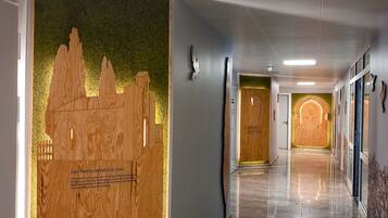 A hallway with a wooden panel featuring a cityscape and text, a polished marble floor, and a series of doors leading to rooms.