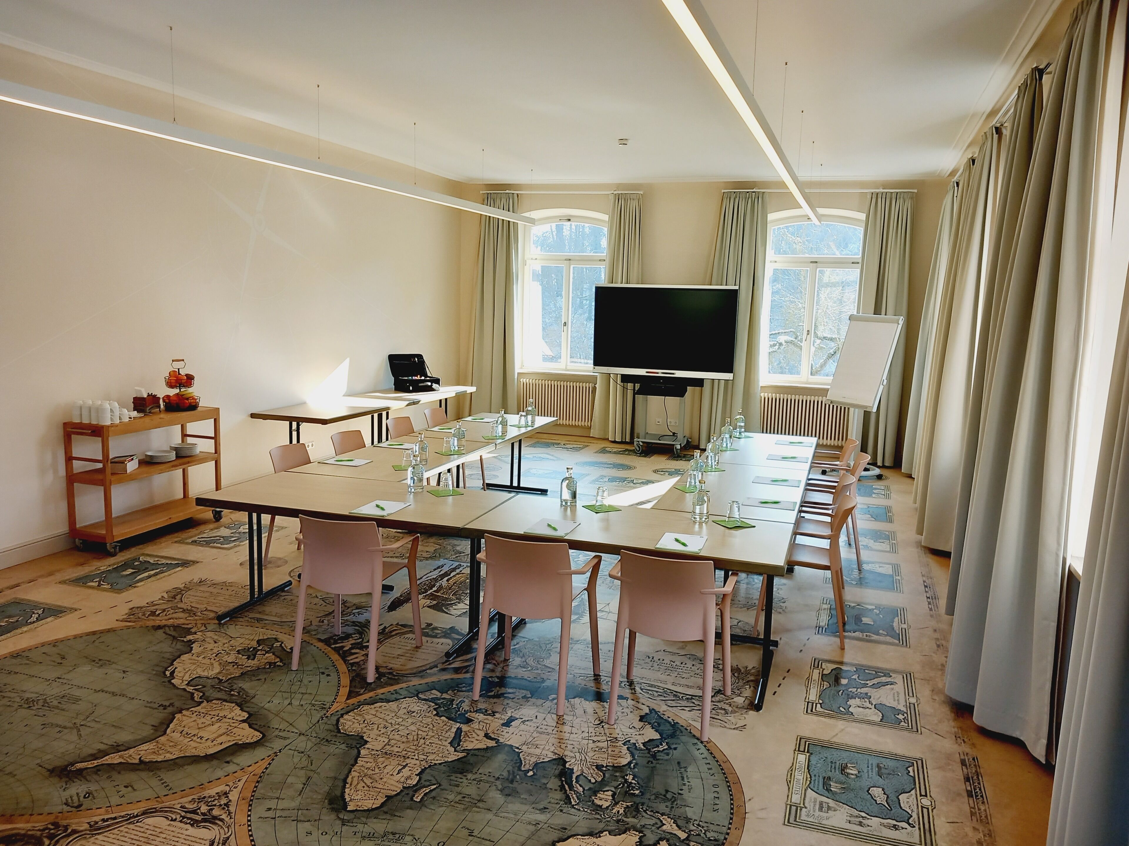 A conference room with a large table, chairs, a television, and a whiteboard.