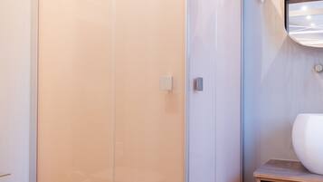 Un baño moderno con ducha envuelta en vidrio, tocador de madera y retrete.