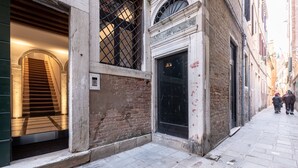 Un vicolo stretto con un edificio che presenta una scala, un'ampia finestra e un portone.