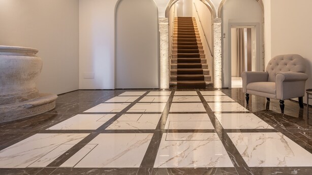 Un'ampio ingresso con pavimento in marmo, una maestosa scalinata e un'ampia urna di pietra.