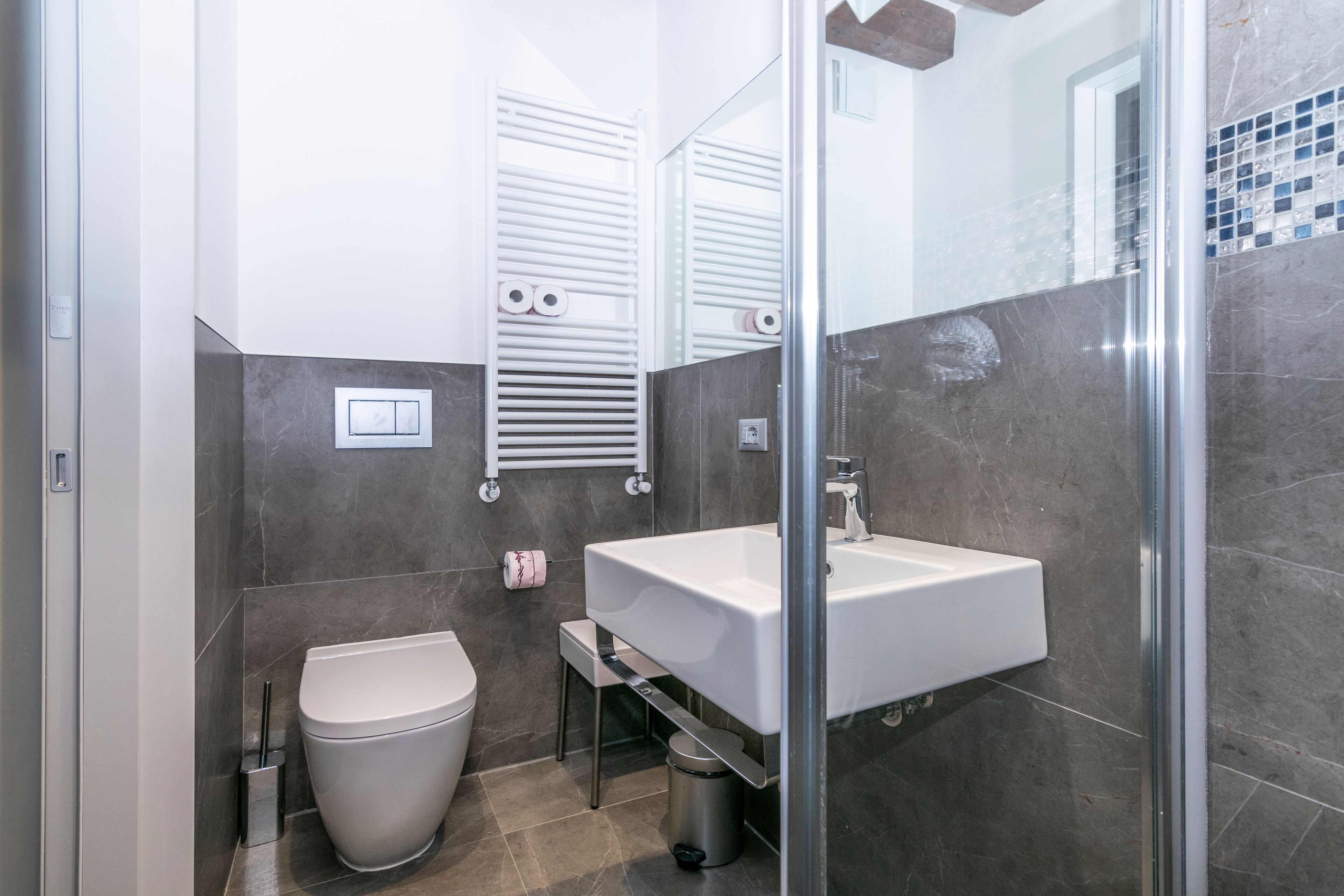 Un baño moderno con lavamanos blanco, inodoro y cabina de ducha de vidrio.