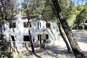 A white building with multiple windows and doors, surrounded by trees.