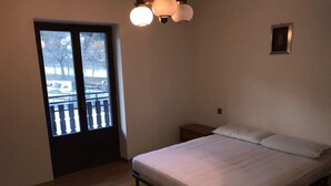 Ein Schlafzimmer mit einem Bett, einem Nachttisch, einem kleinen Tisch und einer Tür, die auf einen Balkon führt.