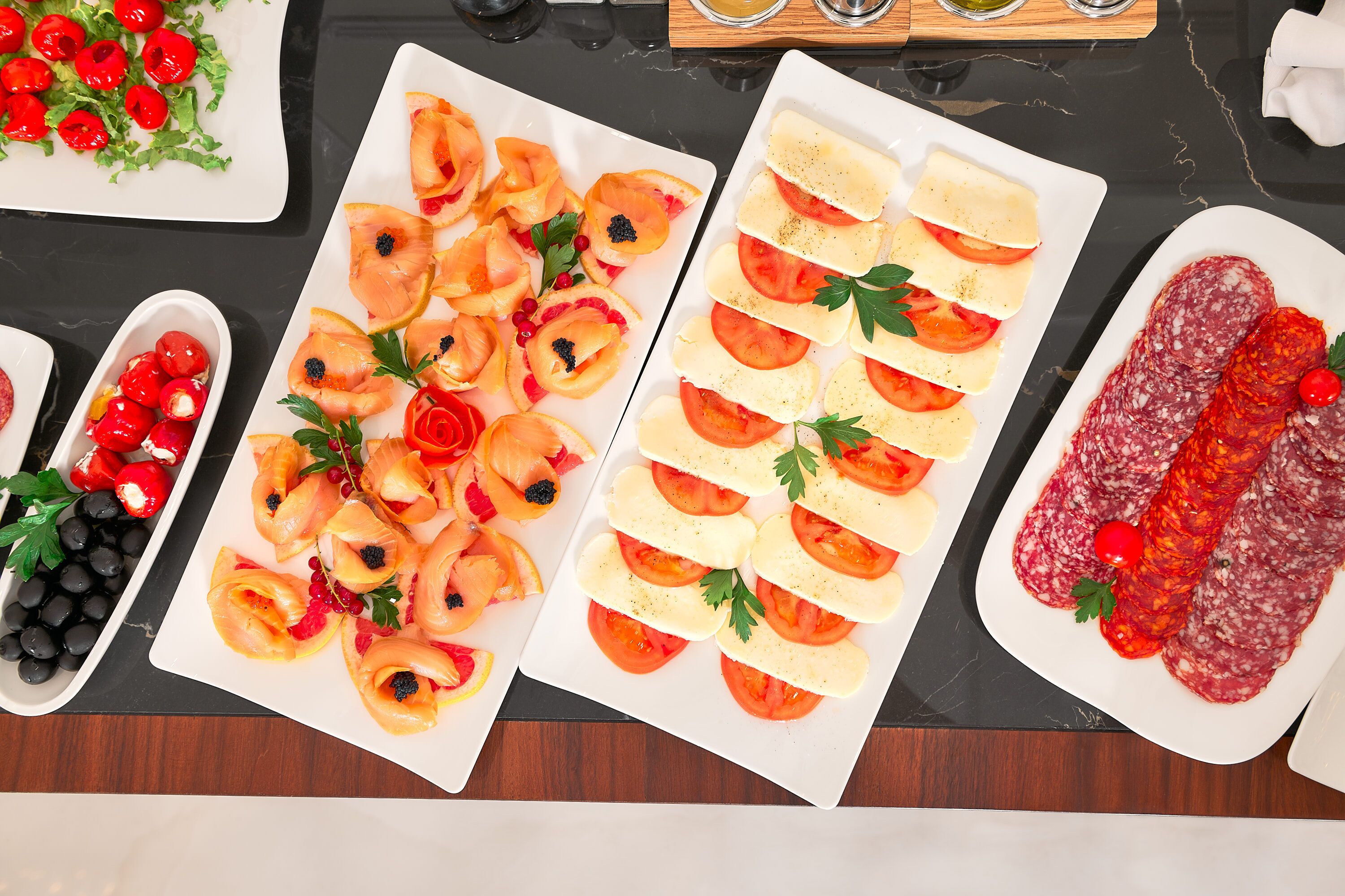 Uma mesa com diversos alimentos, incluindo tomates fatiados, queijo e embutidos.