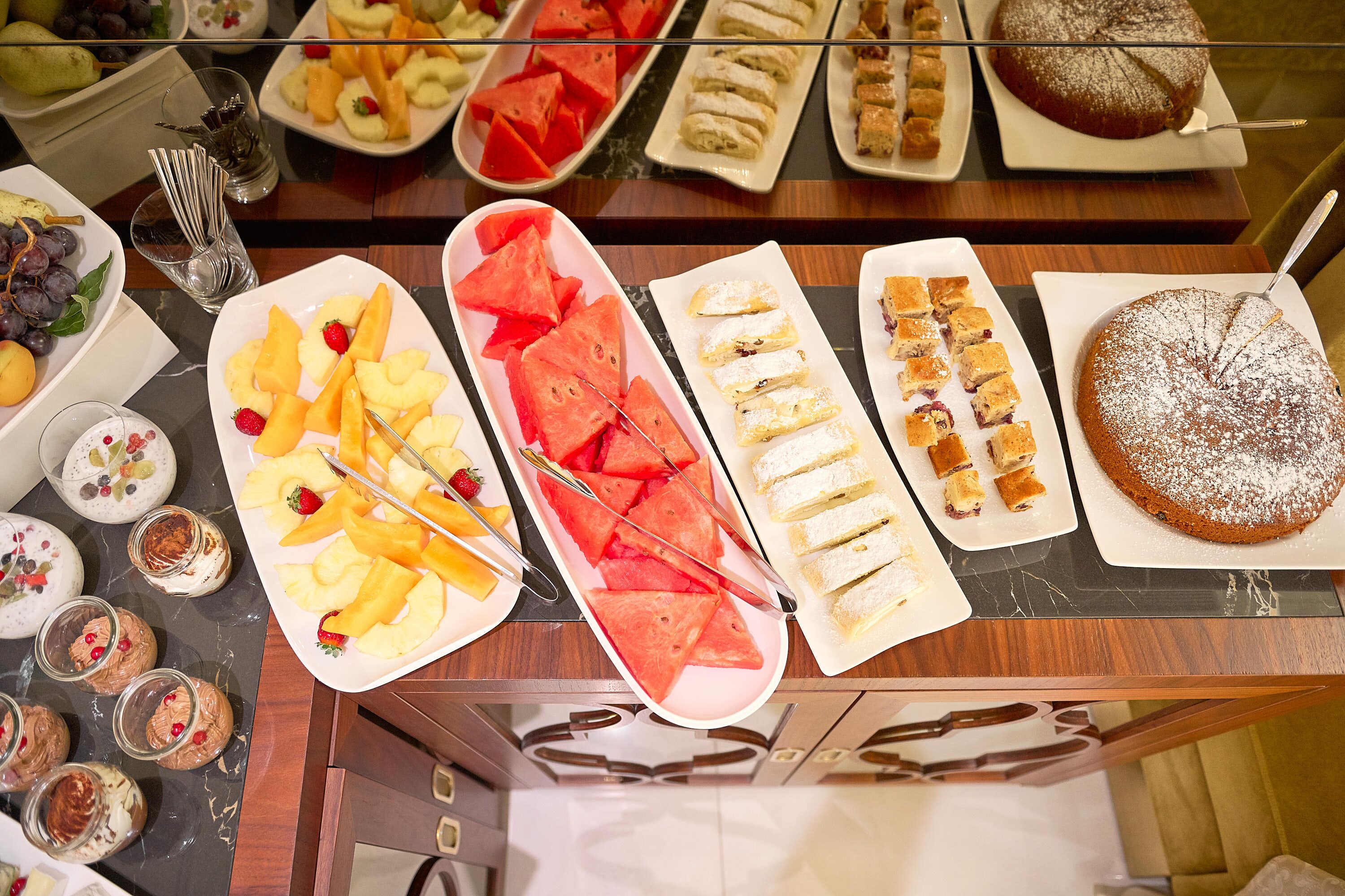 A buffet with various food items including fruits, pastries, and desserts.