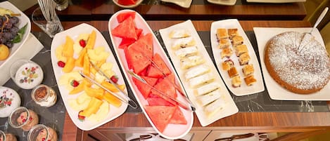 A buffet with various food items including fruits, pastries, and desserts.