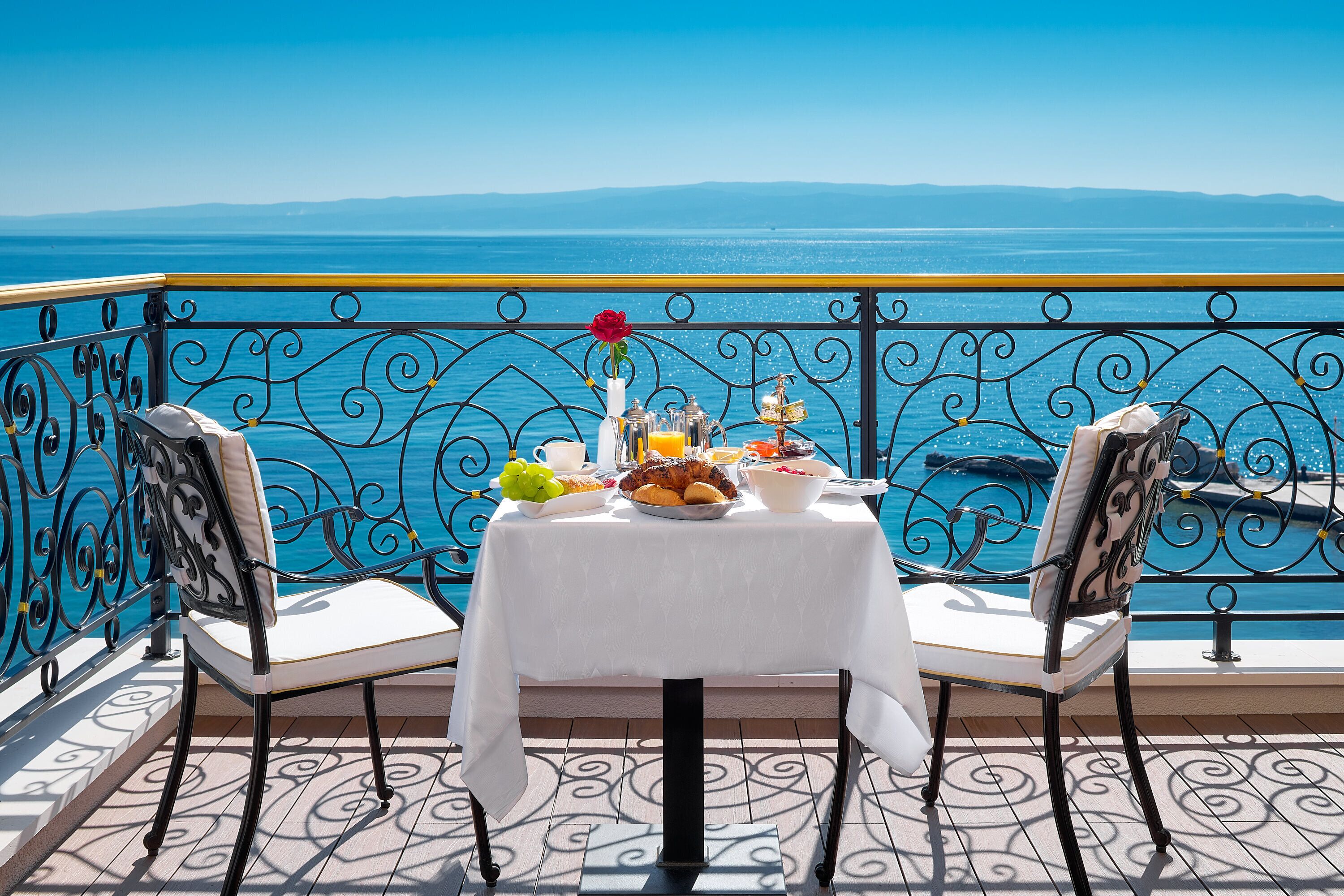 Mesa para dos con vista al mar, barandilla decorativa y piso estampado.