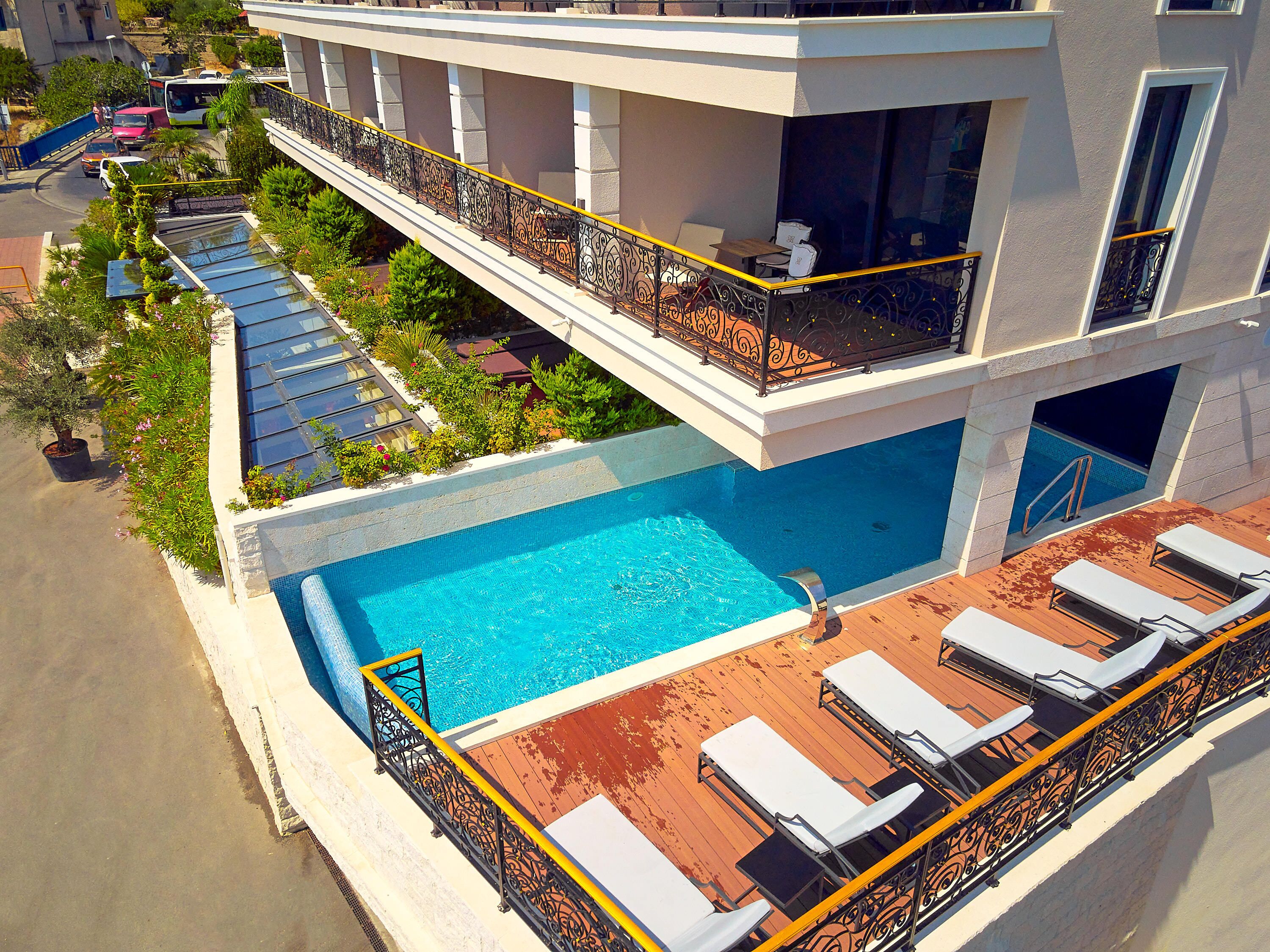 A rooftop swimming pool with sun loungers and a balcony with a railing.