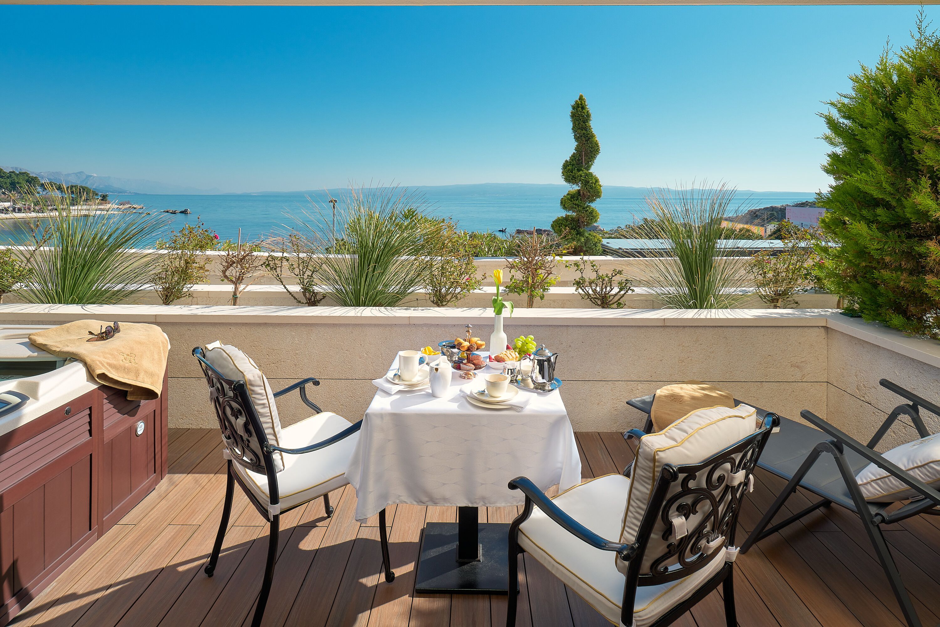 A patio with a table set for breakfast, overlooking a scenic ocean view.
