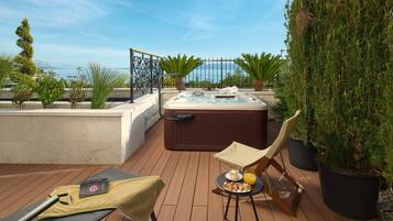 Una terraza en la azotea con hidromasaje, sillones de descanso y una mesa con aperitivos y bebidas.