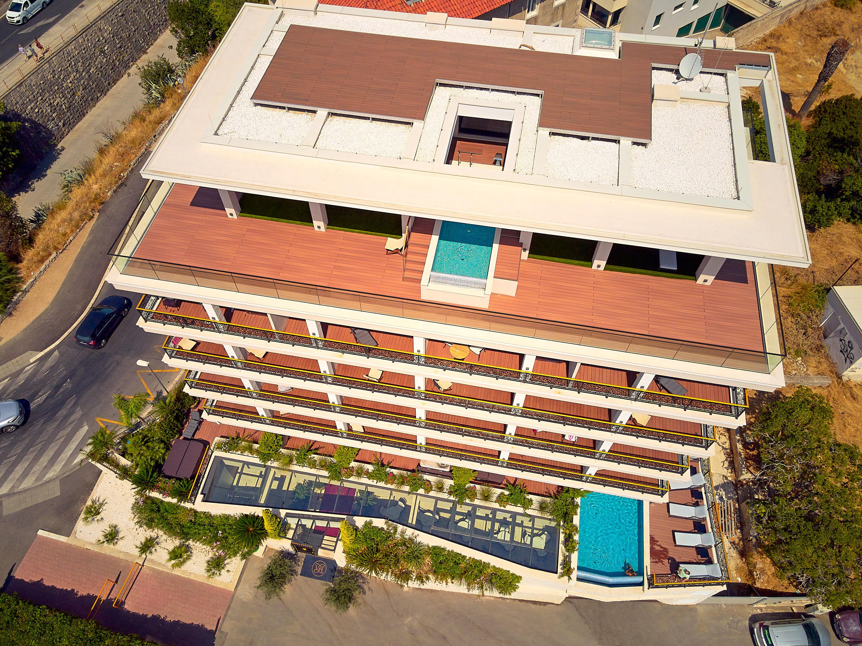 Un hôtel à plusieurs étages doté d’une piscine sur le toit, d’un espace extérieur aménagé et d’un jardin paysager.