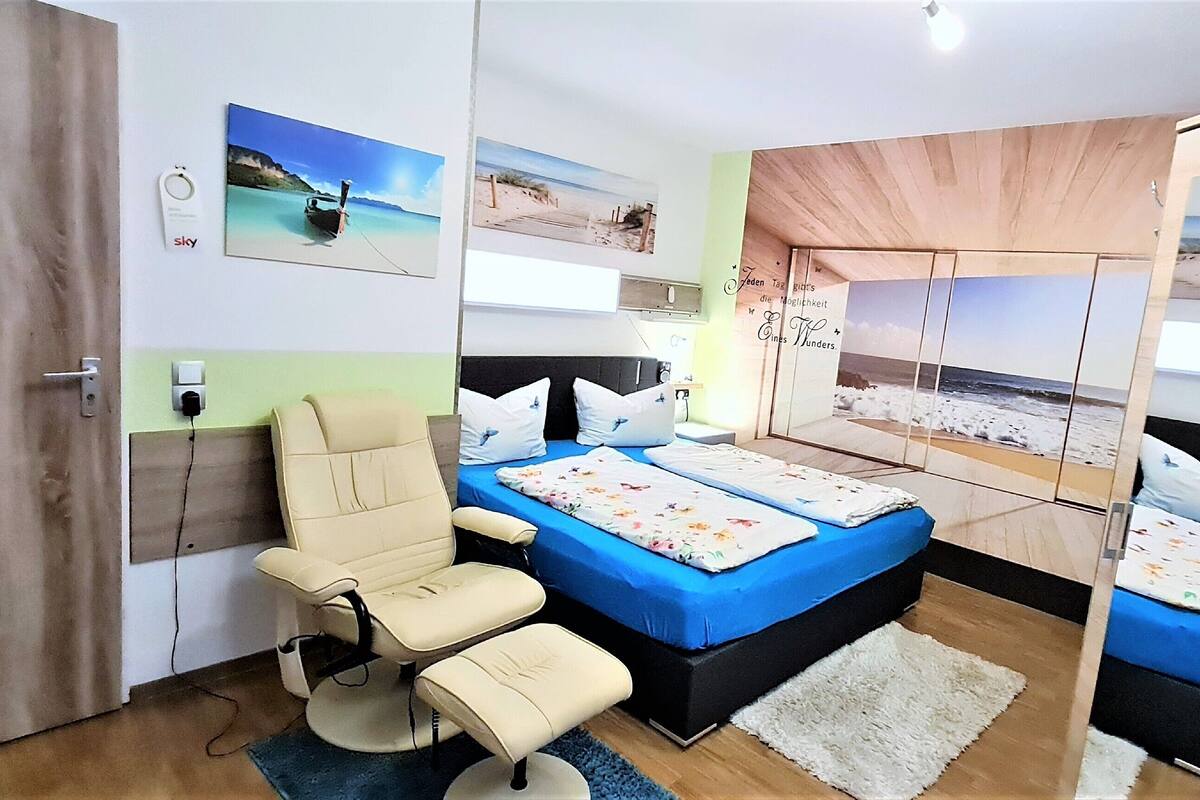 A bedroom with a bed, a chair, and a wardrobe.
