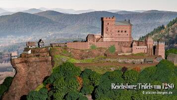 A historic castle with a prominent tower, situated on a cliff overlooking a valley.