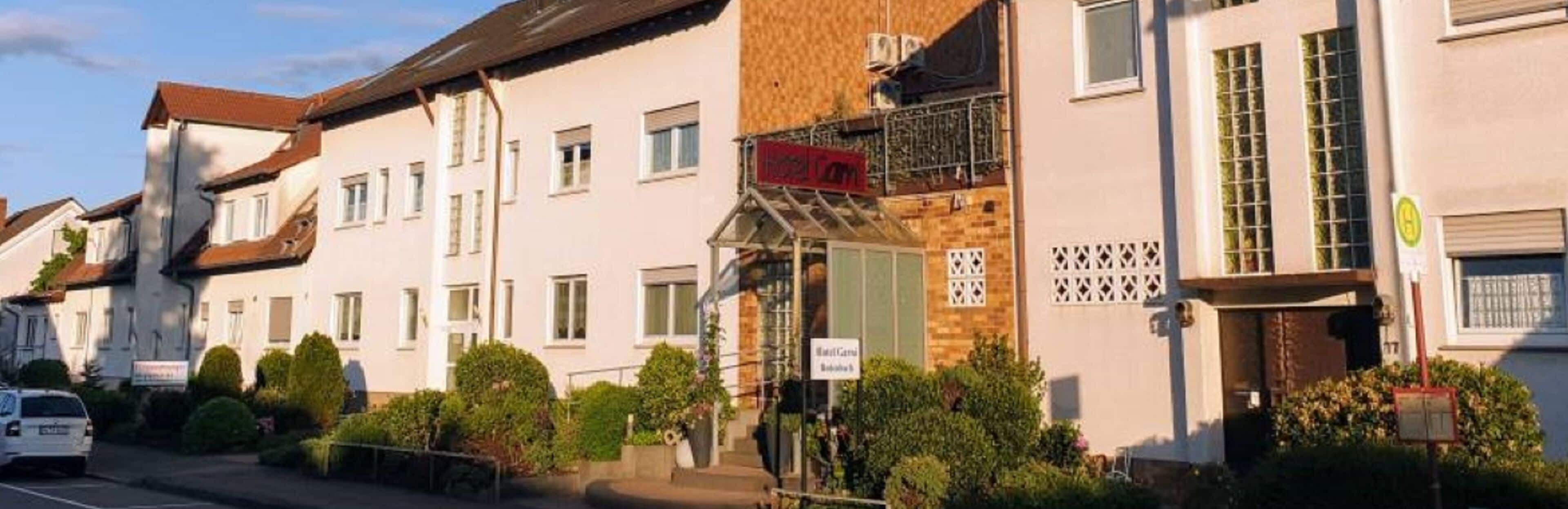 A row of white buildings with a sign for a hotel on the right.