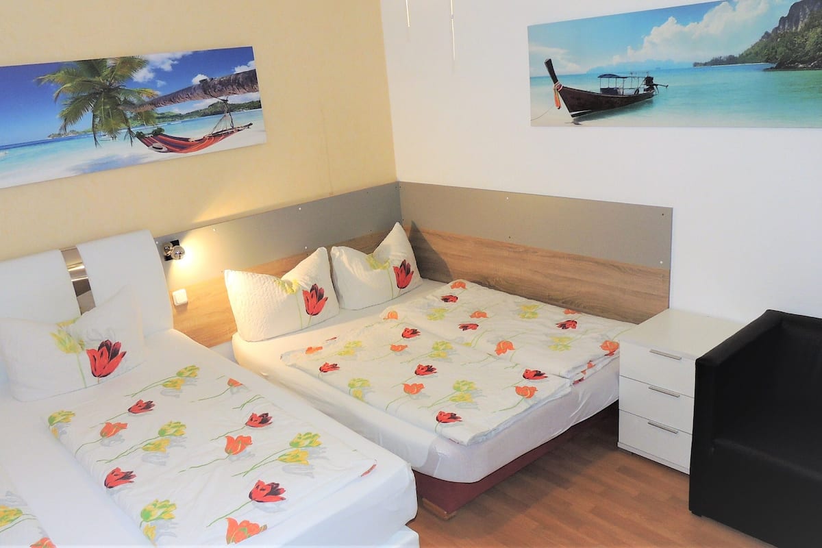 A hotel room with two beds, each with floral bedding, a wooden headboard, and a small desk with drawers.