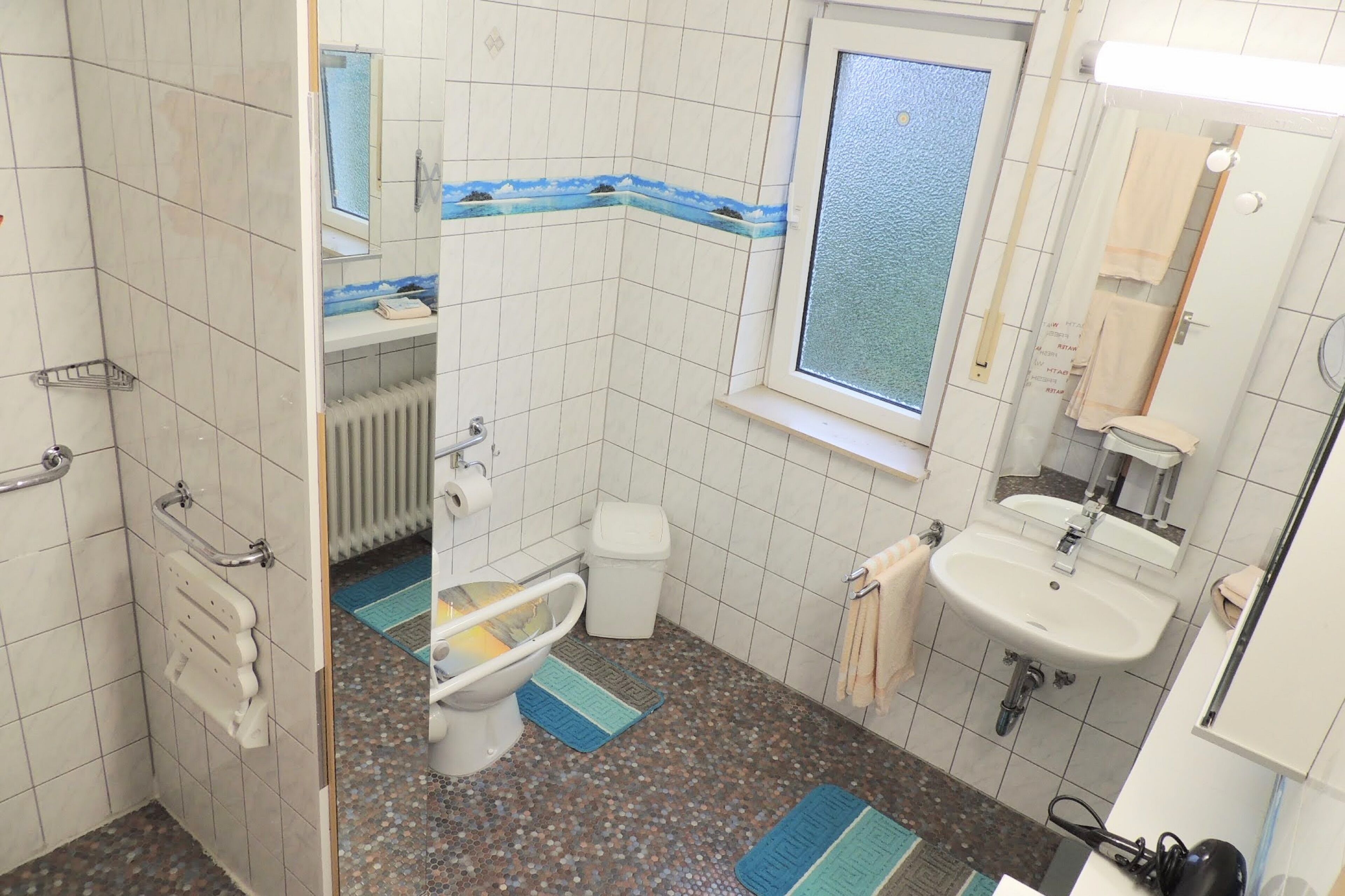 Un baño con inodoro, bidé, lavamanos y ventana.